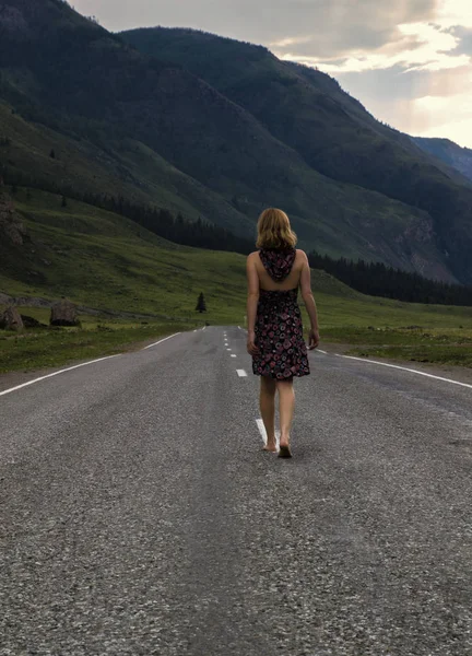 Mujer sola descalza está caminando a lo largo de la carretera de montaña. Concepto de viajes, turismo y personas — Foto de Stock