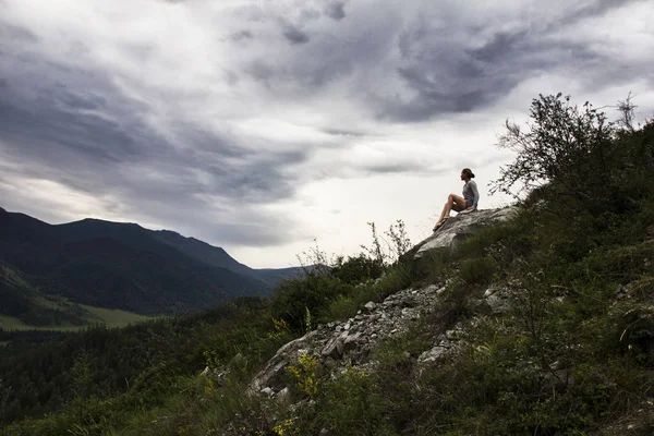 Dağın tepesinde oturan ve gökyüzü bulutlar düşünürken güzel kadın