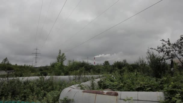 Verontreiniging van de natuur, groene veld en rook uit industriële leidingen — Stockvideo