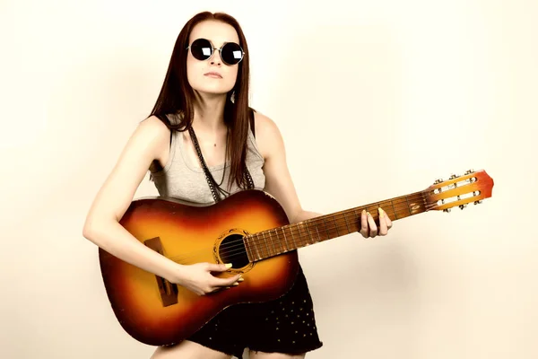 Young beautiful hippie playing guitar on light background — Stock Photo, Image