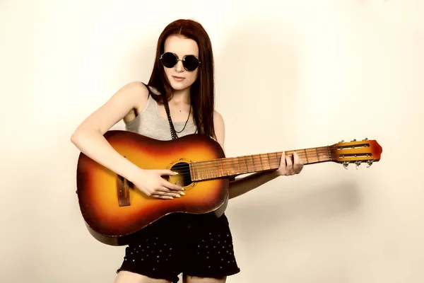Young beautiful hippie playing guitar on light background — Stock Photo, Image