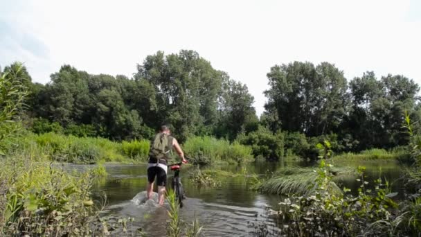 Mountainbiker rijden in de rivierbedding — Stockvideo