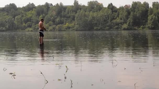 Pescador semi-nu com uma pesca vara no rio calmo — Vídeo de Stock