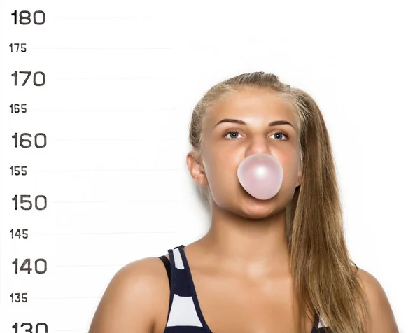 Joven hermosa mujer rubia masticando chicle y soplando burbujas Criminal Taza disparos —  Fotos de Stock
