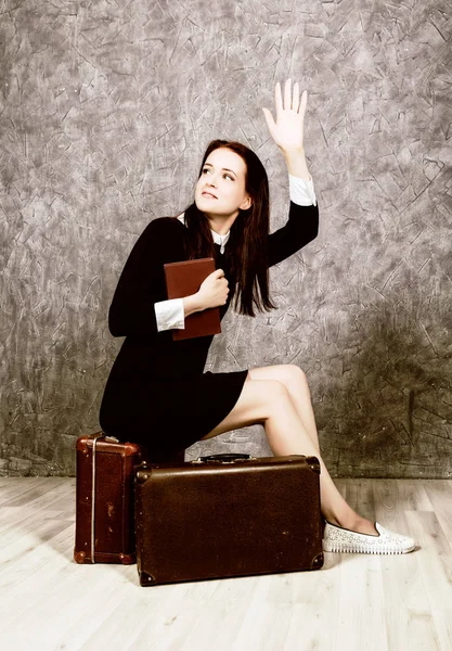Retro woman with suitcase reading book waiting for a meeting, vintage style.