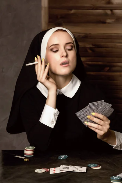 Mooie katholieke non rookt en speelkaarten. Rotte religie — Stockfoto