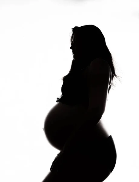 Silhouette di una bella donna incinta su uno sfondo bianco — Foto Stock