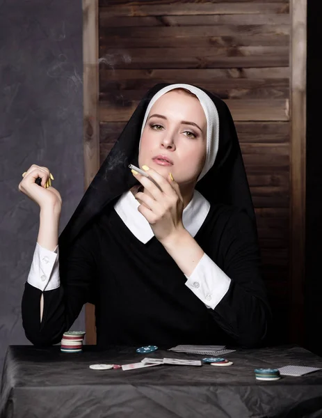 Hermosa monja católica fuma y juega a las cartas. Religión podrida — Foto de Stock