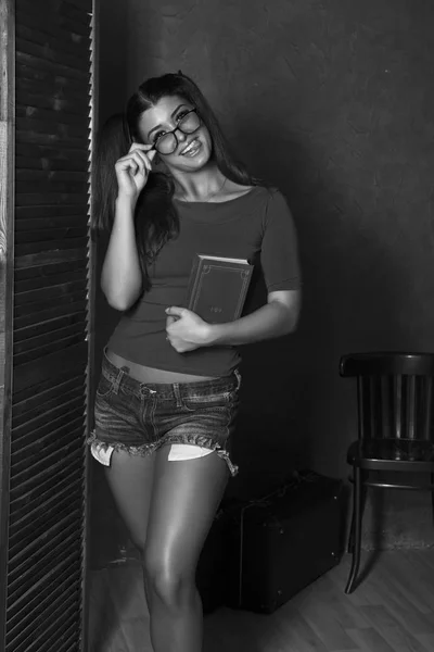 Hermosa estudiante con libro. mujer joven en top rojo y pantalones cortos de mezclilla con gafas —  Fotos de Stock