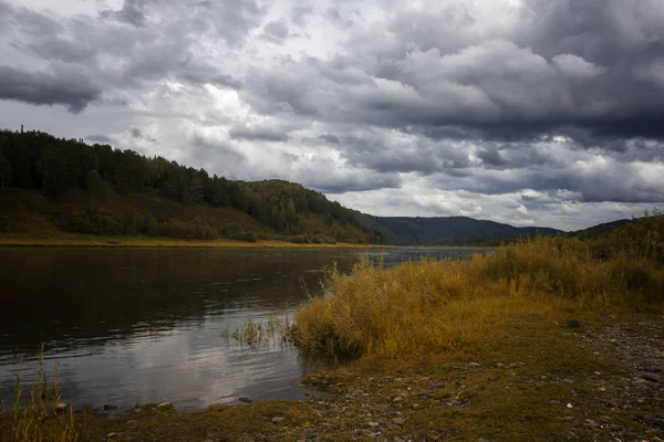 Landschaft mit Fluss, Bergen und Wald an einem Ufer. Himmel mit Gewitterwolken über dem Fluss — Stockfoto