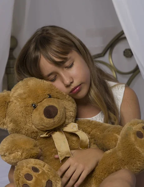 Erken uyanma. Çalar saat ayakta başucundaki. Oyuncak ayı yatakta bir arka plan üzerinde tutan bir uykuda genç kızın uyan