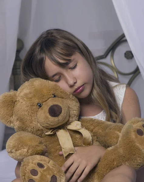 Erken uyanma. Çalar saat ayakta başucundaki. Oyuncak ayı yatakta bir arka plan üzerinde tutan bir uykuda genç kızın uyan