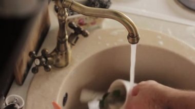 adam bir bulaşıkları yıkar, köpük ve deterjan plakaları durulama