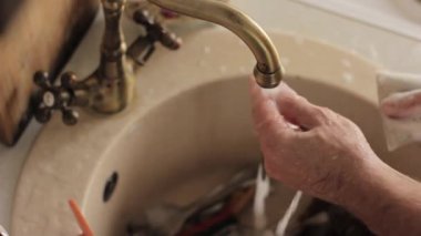 yakın çekim ellerini yıkar bir yemekler mans, su jeti tabaklar köpük ve deterjan durulama