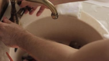 yakın çekim ellerini yıkar bir yemekler mans, su jeti tabaklar köpük ve deterjan durulama