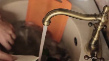 yakın çekim ellerini yıkar bir yemekler mans, su jeti tabaklar köpük ve deterjan durulama