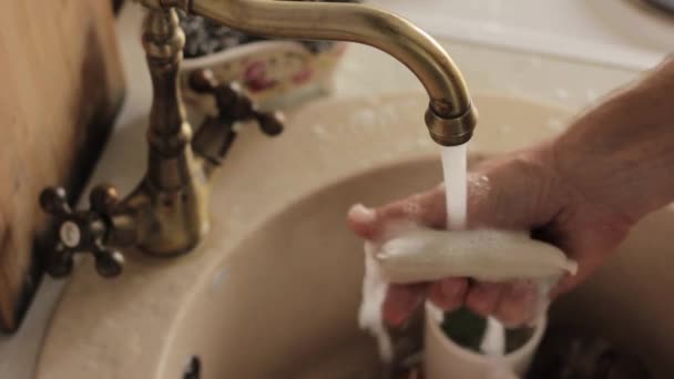Man zmywa naczynia, spłukuje płyty z pianki i detergentów — Wideo stockowe