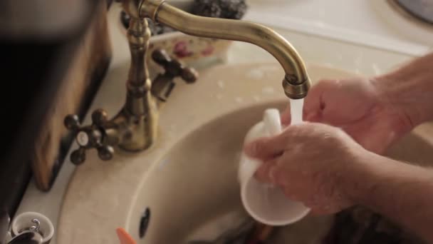 Zbliżenie mans ręce myje naczynia, strumieniem wody płukanie płyty z pianki i detergentów — Wideo stockowe