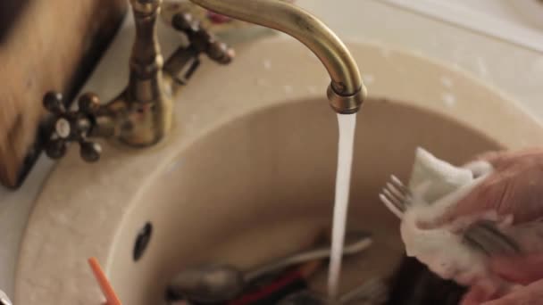 Крупним планом руки чоловіка миють посуд, водяний струмінь змиває тарілки з піни і миючого засобу — стокове відео