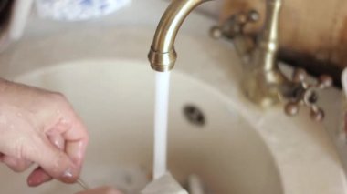 yakın çekim ellerini yıkar bir yemekler mans, su jeti tabaklar köpük ve deterjan durulama