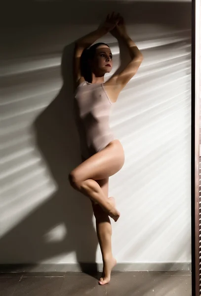 Sexig kvinna i en beige baddräkt i en skugga stripe — Stockfoto