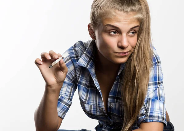 Jovem mulher bonita em camisa quadriculada fumar maconha em um fundo branco . — Fotografia de Stock