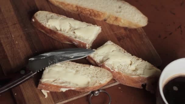 Разбрасывание масла на кусок пшеничного сельского хлеба на деревянной доске — стоковое видео