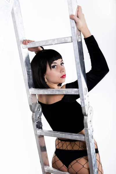 Aantrekkelijke jonge brunette vrouw in ondergoed is staande op een ladder — Stockfoto