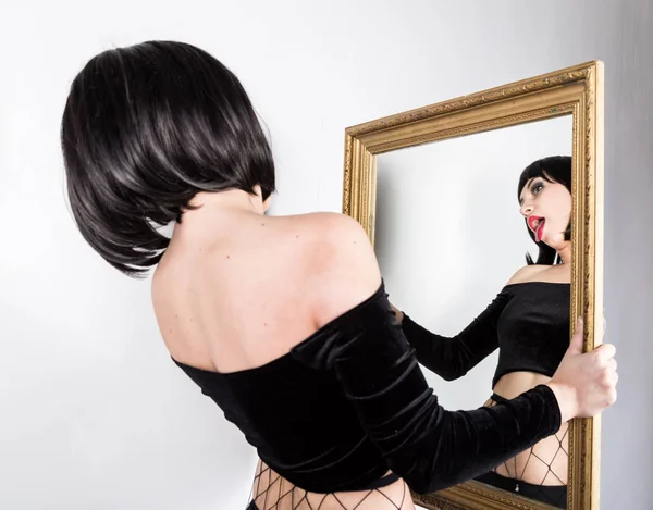 Étrange femme brune faire des visages et se regarder dans le miroir — Photo