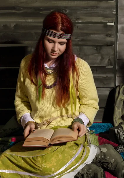 Joven hippie boho pelirroja leer libro sobre un fondo de pared de madera — Foto de Stock