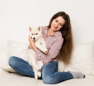 Mutlu güzel kadın kucaklama köpek yavrusu husky. bir köpek ile bir kanepede oturan kız