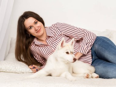 Onu evde beslenen hayvan ile bir kanepede oturan mutlu güzel kadın. Kız sarılma köpek yavrusu husky