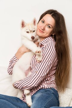 Mutlu güzel kadın kucaklama köpek yavrusu husky. bir köpek ile bir kanepede oturan kız