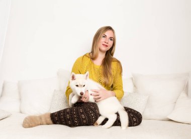 sarışın kadın bir pijama ve Yün çorap beyaz bir yatakta husky köpek yavrusu yalanlarla
