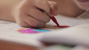 Yakın çekim çocuk elleri kalem ile. Çocuk renkli kalemle kağıt üzerinde çizer..