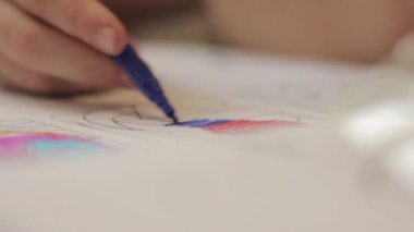 Yakın çekim çocuk elleri kalem ile. Çocuk renkli kalemle kağıt üzerinde çizer..