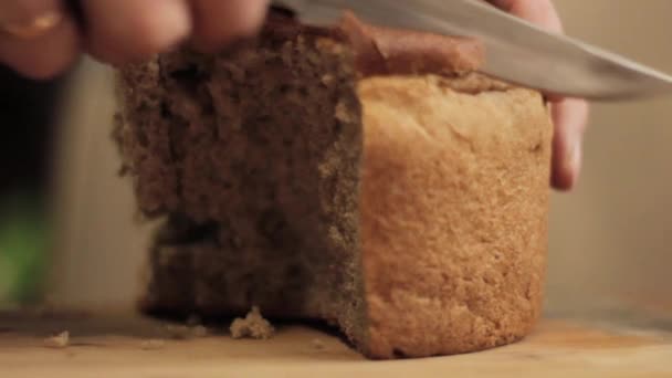 Нарізаний сірий хліб. Крупним планом рука людини з ножем — стокове відео