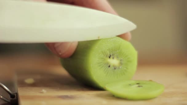A cortar um quivi. Close-up mão homem com faca — Vídeo de Stock