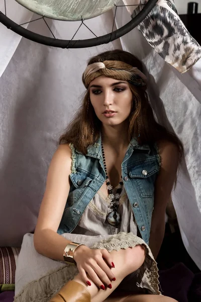 Joven hippie alegre sentado en una almohada suave en una tienda de seda — Foto de Stock