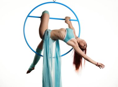 Genç Kızıl saçlı kadın beyaz bir arka plan üzerinde hava ringde akrobatik öğeleri gerçekleştirir