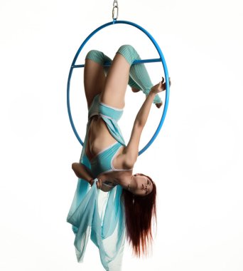 Genç Kızıl saçlı kadın beyaz bir arka plan üzerinde hava ringde akrobatik öğeleri gerçekleştirir