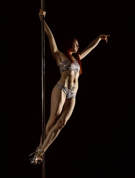 Young redhead athletic pole dance girl in a swimsuit on a black studio background — Stock Photo, Image