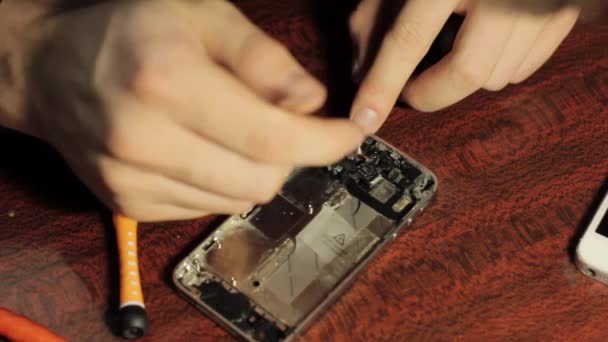 Master repairs cell phone. Chips and details of the smartphone. — Stock Video