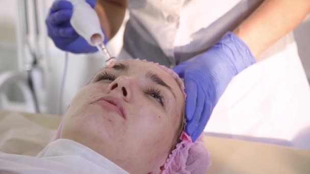 Косметолог занимается уходом за кожей лица с помощью электрического дарсонвала. Косметическая процедура — стоковое видео