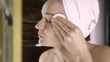 Bir havlu güzel kadın aynanın önünde makyaj kapalı alır. Evde Spa