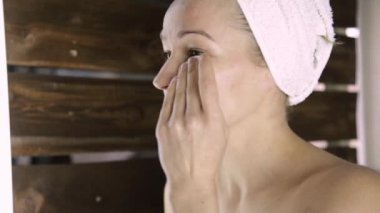 Bir havlu güzel kadın aynanın önünde makyaj kapalı alır. Evde Spa