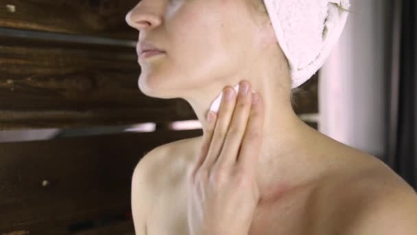 Vacker kvinna i en handduk tar bort makeup framför spegeln. Spa hemma — Stockvideo
