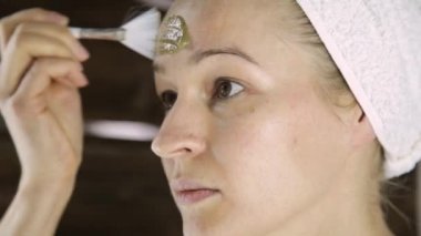 Havlu uygulanmasında güzel kadın Yeşil Kil çamur maskesi yüzüne karşı. Cilt Bakımı ve ev Spa