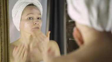 Nemlendirici krem yüzüne koydu bir havlu güzel sağlıklı kadın. Cilt Bakımı ve ev Spa