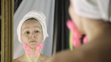 güzel kadın kozmetik prosedürler içinde ev işi havlu. yüz masaj masaj aleti ile